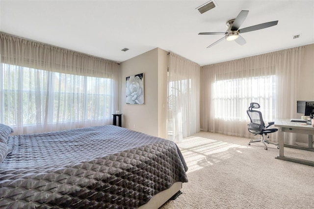 carpeted bedroom featuring multiple windows and ceiling fan