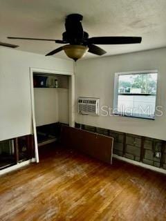 interior space with hardwood / wood-style flooring, a wall mounted AC, ceiling fan, and a closet