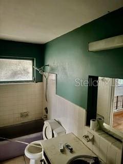 bathroom featuring tile patterned flooring, shower / washtub combination, and toilet