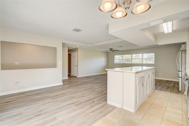 kitchen with white cabinets, ceiling fan with notable chandelier, light wood-type flooring, and a center island