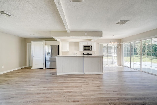 kitchen with hanging light fixtures, appliances with stainless steel finishes, white cabinets, a notable chandelier, and light hardwood / wood-style floors