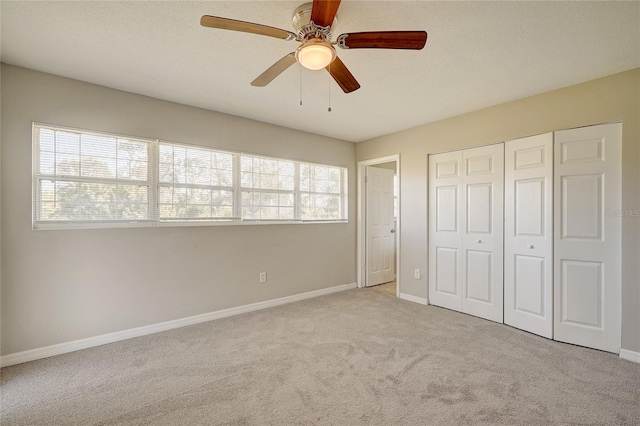 unfurnished bedroom with ceiling fan, a closet, and light carpet