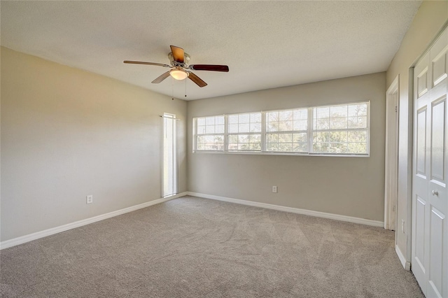 unfurnished bedroom with light carpet, a textured ceiling, a closet, and ceiling fan