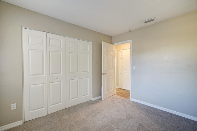 unfurnished bedroom with light colored carpet and a closet