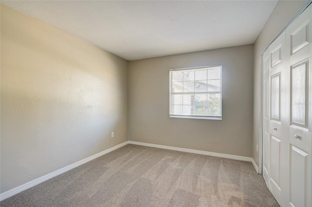 unfurnished bedroom featuring carpet floors, a textured ceiling, and a closet