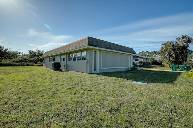 view of side of property featuring central AC unit and a lawn