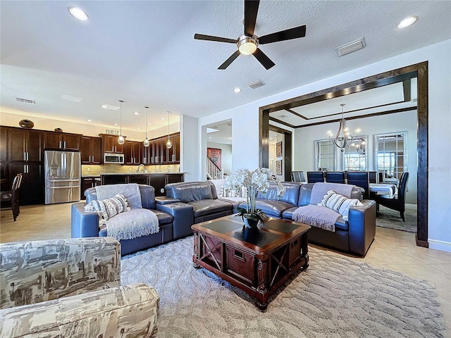 living room with ceiling fan with notable chandelier and a textured ceiling