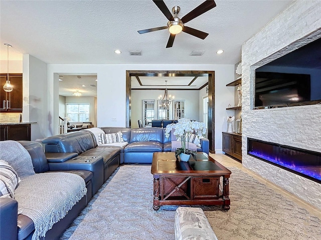 carpeted living room with a stone fireplace, an inviting chandelier, and a textured ceiling