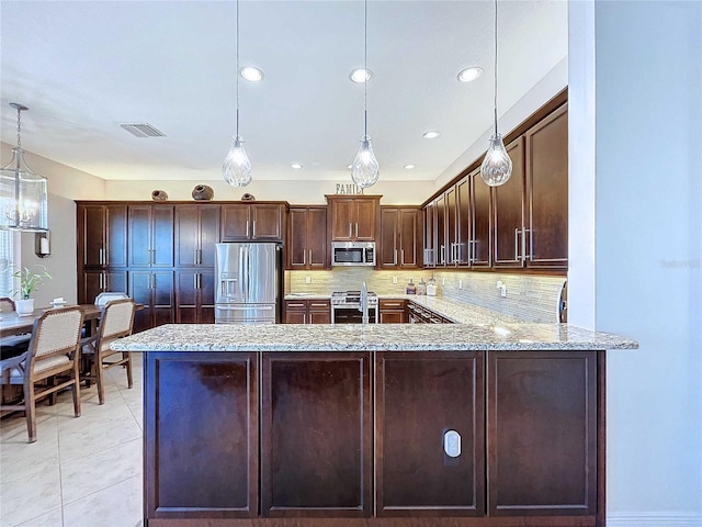 kitchen with appliances with stainless steel finishes, decorative light fixtures, backsplash, kitchen peninsula, and light stone countertops