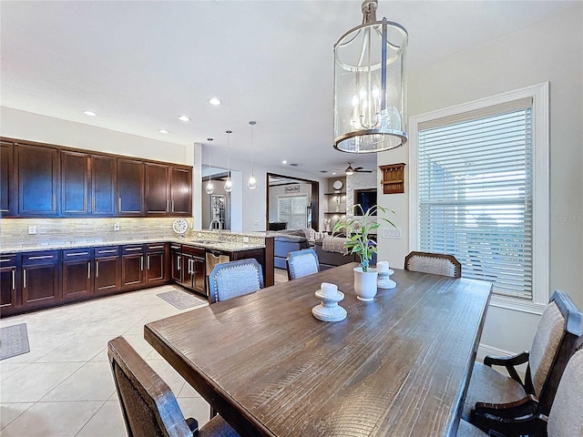 dining space with light tile patterned floors, ceiling fan with notable chandelier, and sink