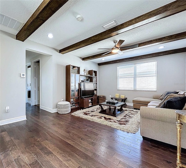 living room featuring dark wood-type flooring, ceiling fan, beam ceiling, and a textured ceiling