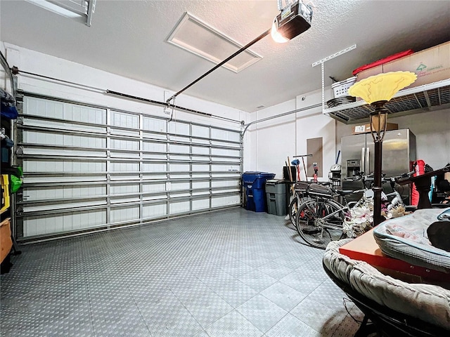 garage featuring stainless steel refrigerator with ice dispenser and a garage door opener