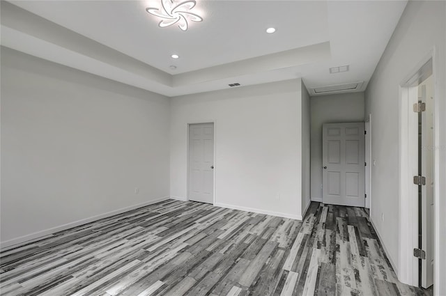 empty room with light hardwood / wood-style floors and a tray ceiling