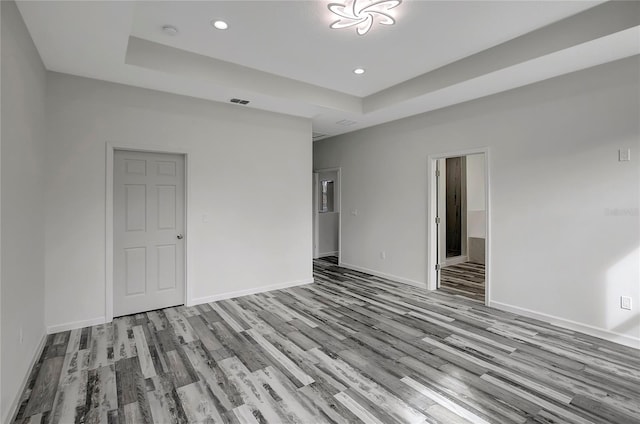 empty room featuring light hardwood / wood-style flooring and a tray ceiling