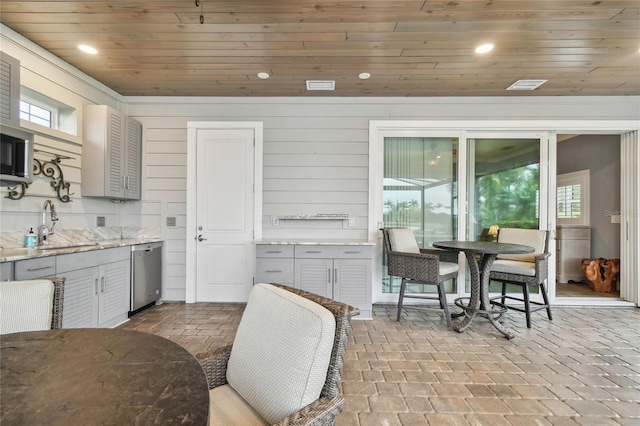 kitchen featuring a wealth of natural light, wooden ceiling, dishwasher, wooden walls, and sink