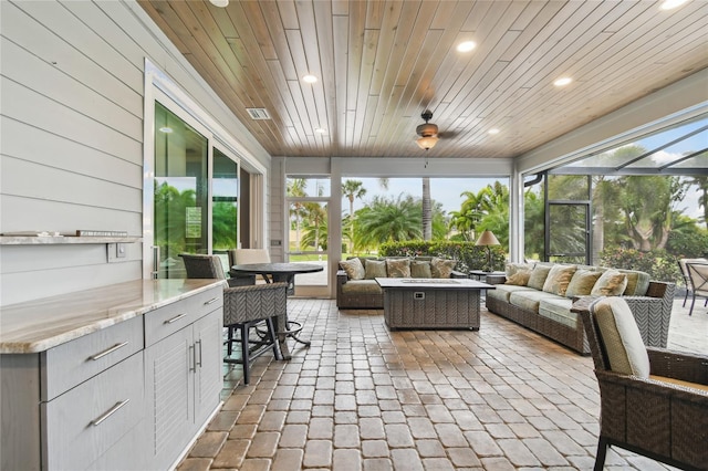 sunroom with wooden ceiling, a healthy amount of sunlight, and ceiling fan