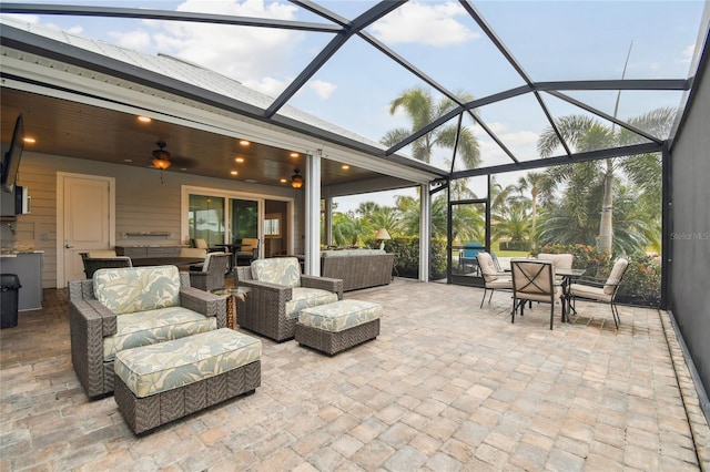 view of patio / terrace featuring glass enclosure, outdoor lounge area, and ceiling fan