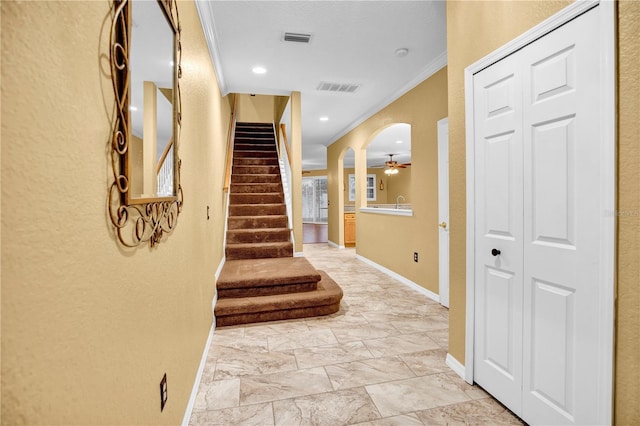 entrance foyer with ceiling fan and ornamental molding