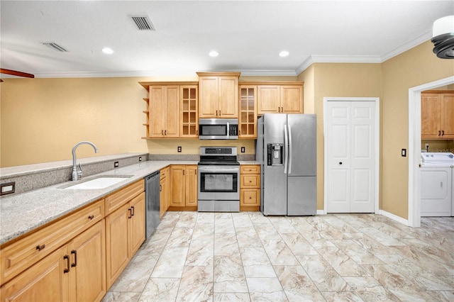 kitchen with light stone countertops, washer / dryer, stainless steel appliances, sink, and crown molding