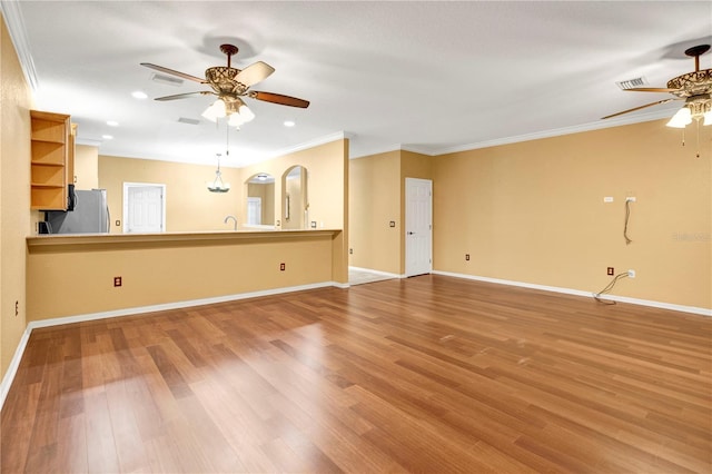 unfurnished living room featuring sink, ceiling fan, crown molding, and hardwood / wood-style floors