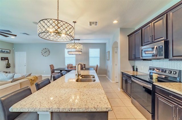 kitchen with pendant lighting, appliances with stainless steel finishes, sink, a kitchen island with sink, and a breakfast bar