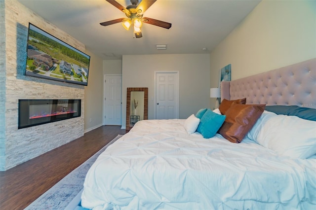 bedroom with ceiling fan, dark hardwood / wood-style flooring, and a fireplace