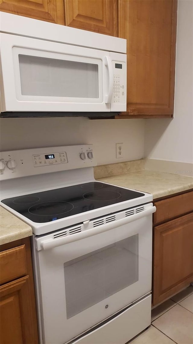 kitchen featuring white appliances and light tile patterned flooring