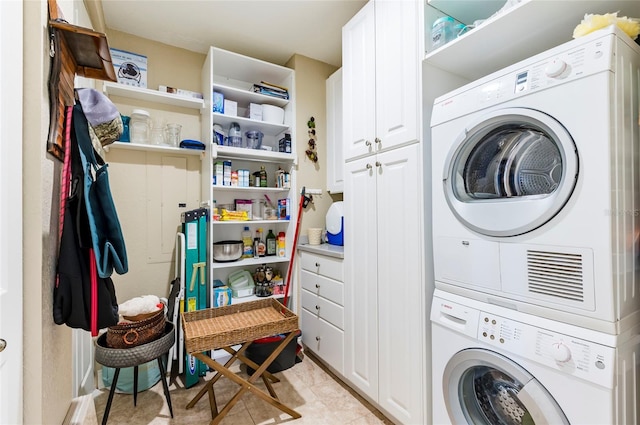 washroom with stacked washer / dryer and cabinets