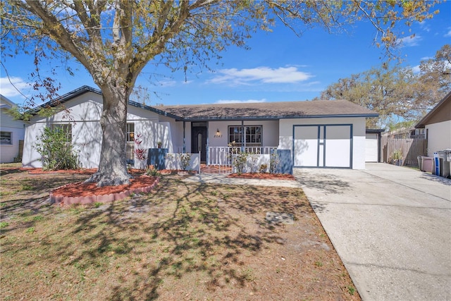 ranch-style house featuring concrete driveway, an attached garage, fence, a porch, and stucco siding