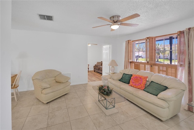 living room featuring a ceiling fan, visible vents, a textured ceiling, and light tile patterned flooring