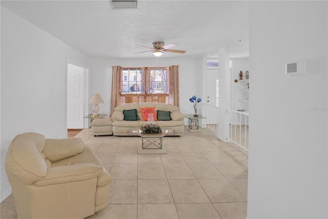 living room with a ceiling fan, visible vents, a textured ceiling, and light tile patterned flooring