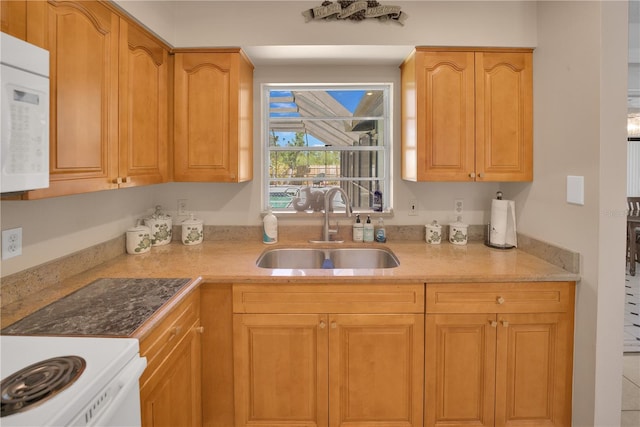 kitchen featuring white appliances, a sink, and light stone counters