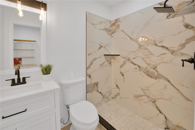 bathroom featuring a marble finish shower, vanity, and toilet