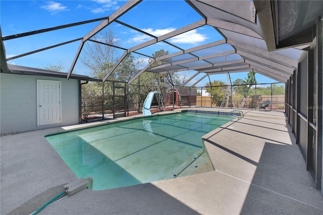 view of swimming pool with glass enclosure, a fenced in pool, a water slide, and a patio