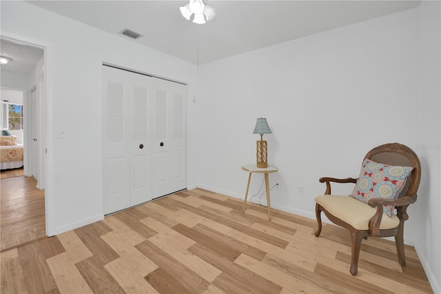 unfurnished room with a textured ceiling, light wood-style flooring, visible vents, and baseboards