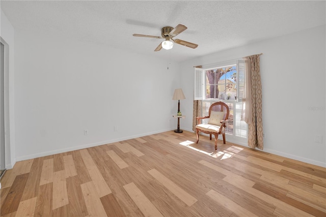 unfurnished room featuring a ceiling fan, light wood-style flooring, baseboards, and a textured ceiling