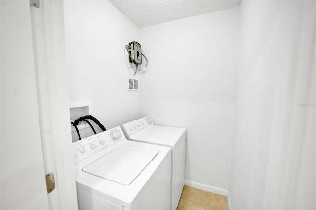 laundry area with visible vents, a textured ceiling, washer and dryer, laundry area, and baseboards