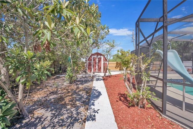 view of yard with a lanai, an outdoor structure, fence, and a storage unit