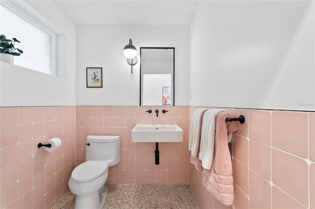 bathroom featuring tile walls and toilet