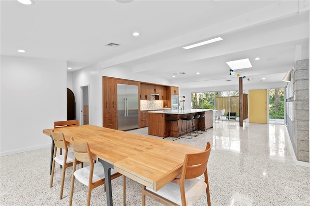 dining space featuring sink and a skylight