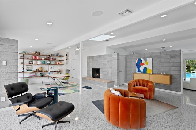 living room with ceiling fan and a tile fireplace