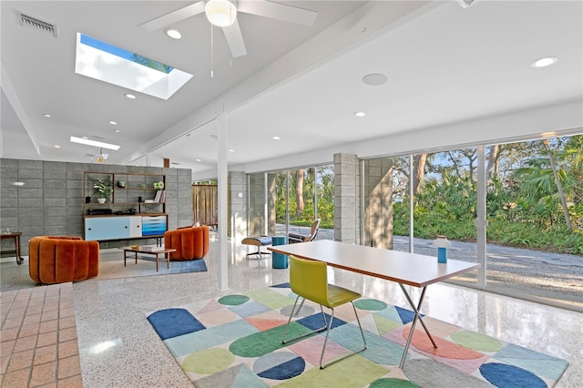 rec room featuring tile walls, ceiling fan, and a skylight