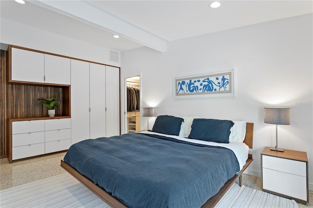 bedroom featuring a spacious closet, beam ceiling, and a closet