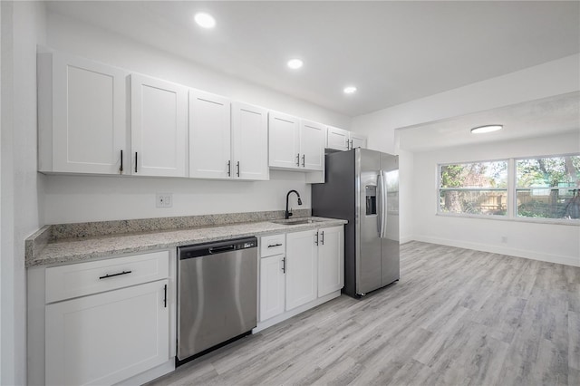 kitchen featuring sink, light stone counters, light wood-type flooring, stainless steel appliances, and white cabinets