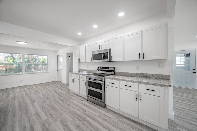 kitchen with light stone countertops, white cabinetry, appliances with stainless steel finishes, and a healthy amount of sunlight