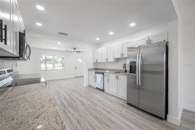 kitchen with light stone counters, light hardwood / wood-style floors, white cabinets, and appliances with stainless steel finishes