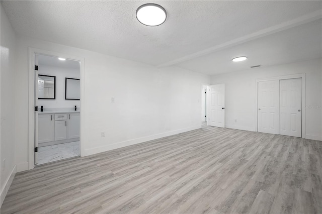 spare room featuring light hardwood / wood-style flooring and a textured ceiling