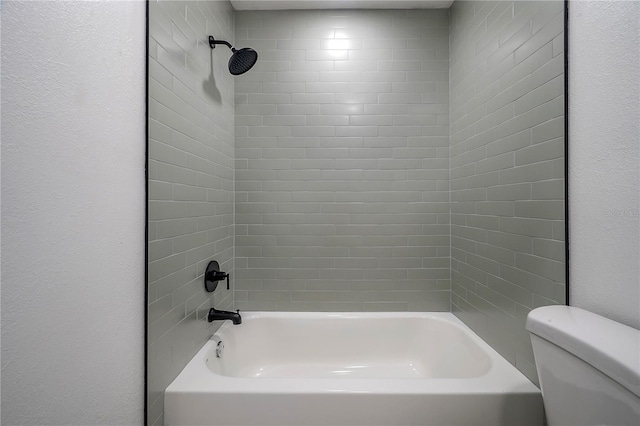 bathroom featuring toilet and tiled shower / bath combo