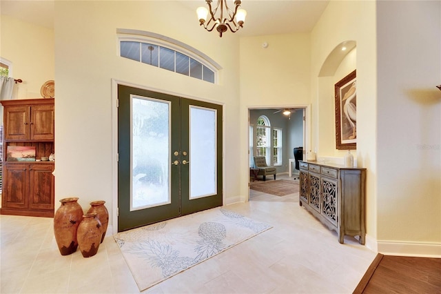 foyer entrance featuring light tile patterned floors, a notable chandelier, and french doors