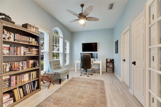 home office with light hardwood / wood-style flooring and ceiling fan